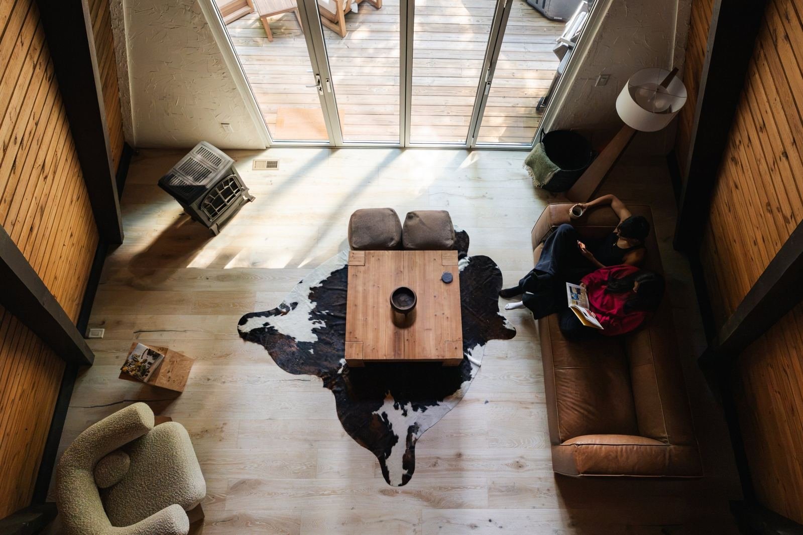 The living room from the loft: cowhide rug, leather sofa, light through the glass gable