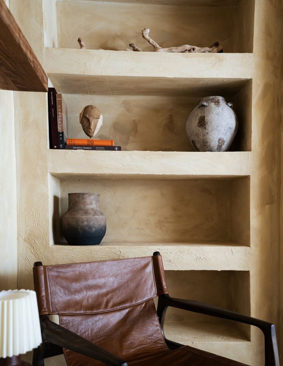 Plaster shelving with ceramics and a leather sling chair